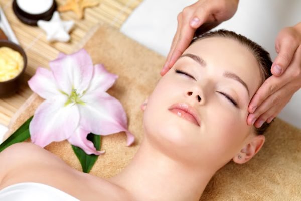 Beautiful young woman having spa massage of the head  in beauty salon - indoors